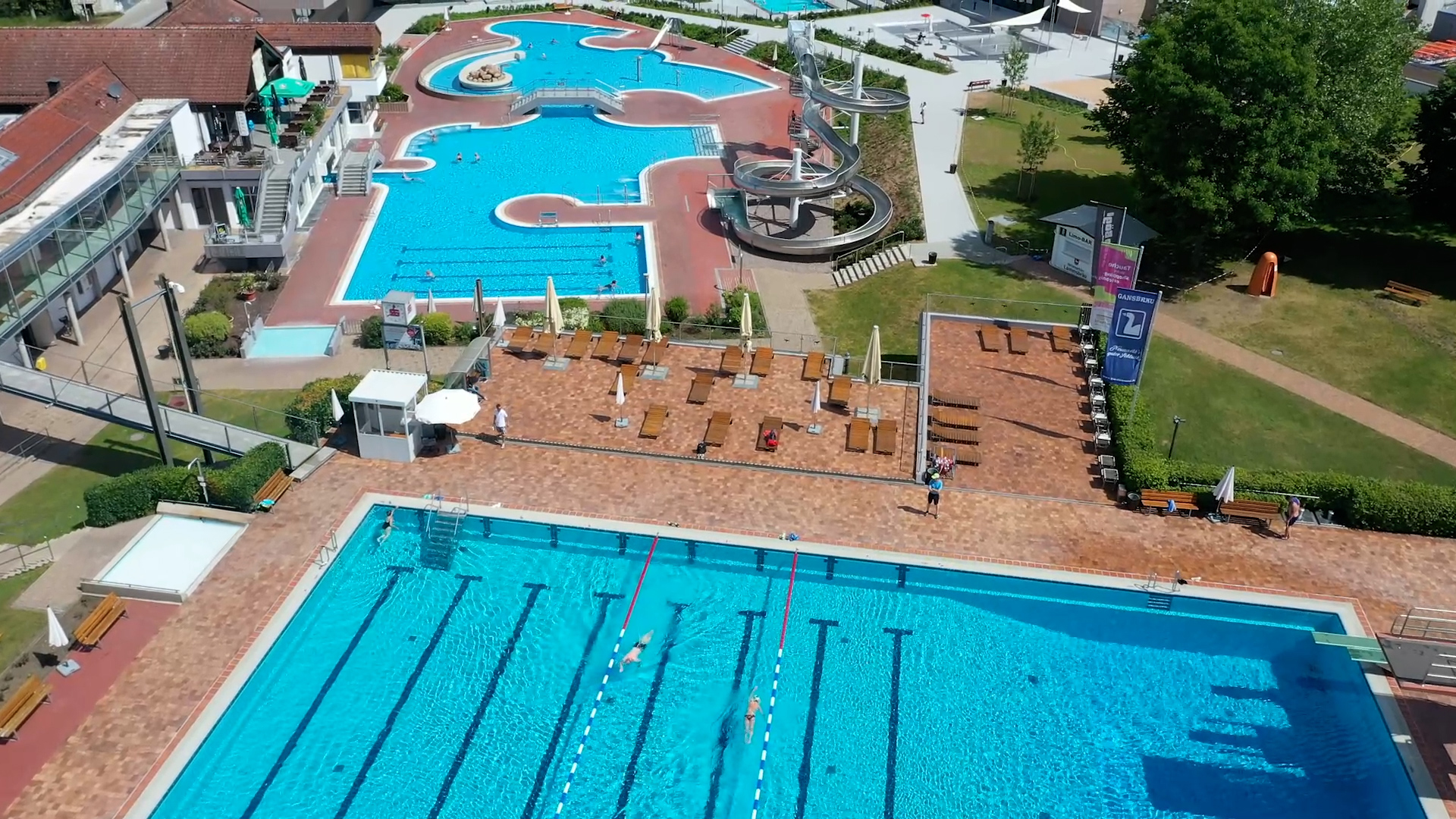 Luftaufnahme des Neumarkter Freibads mit Schwimmerbecken, Erlebnisbecken, Wasserrutsche und Liegebereichen.