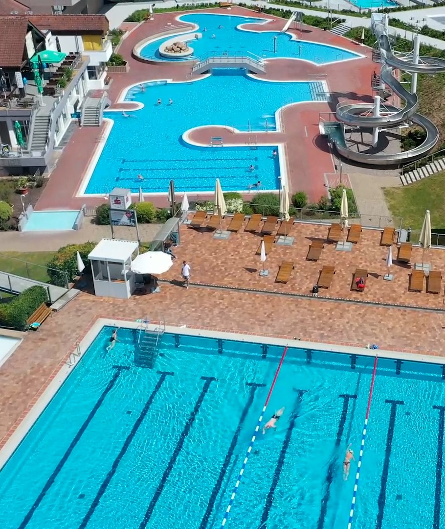 Luftaufnahme des Neumarkter Freibads mit Schwimmerbecken, Erlebnisbecken, Wasserrutsche und Liegebereichen.