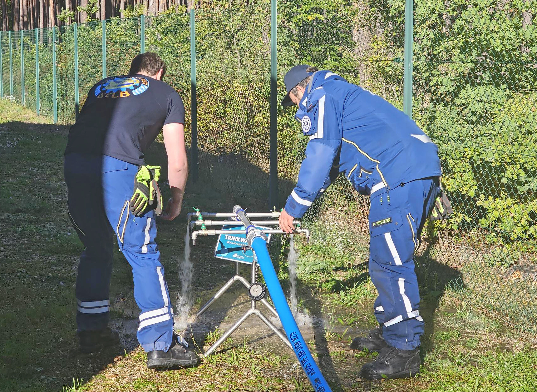 Zwei THW-Einsatzkräfte überprüfen eine mobile Trinkwasser-Ausgabestelle bei einer gemeinsamen Notfallübung mit den Stadtwerken Neumarkt.
